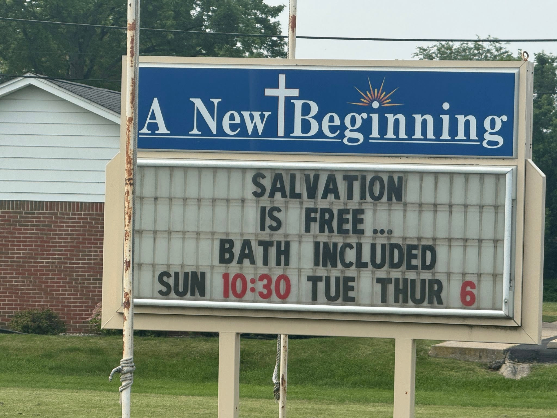 A New Beginning church marquee: 'Salvation is free… bath included. Sun 10:30, Tue Thur 6'